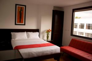 1 dormitorio con 1 cama y 1 sofá rojo en Hotel AW Boutique, en Bogotá