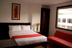 una camera con un letto e un divano rosso di Hotel AW Boutique a Bogotá