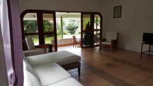 a living room with a couch and chairs and windows at Beau Vallon Bungalows in Beau Vallon