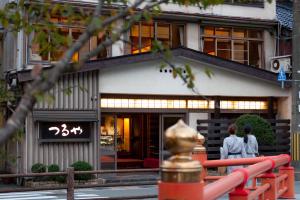 two people standing in front of a building at Tsuruya Ryokan in Toyooka