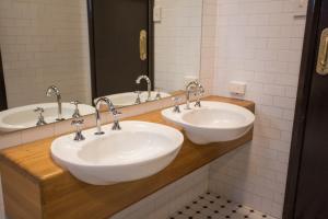Nags Head Hotel في نيوكاسل: حمام بثلاث مغاسل ومرايا