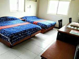 金沙鎮的住宿－祥華酒店，一间卧室配有两张床、一张桌子和两个窗户。