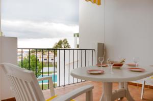 Biały stół i krzesła w pokoju z balkonem w obiekcie Apartamentos Rotonda w mieście Conil de la Frontera