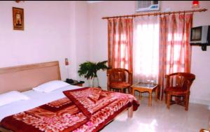 a bedroom with a bed and chairs and a window at Hotel King in Haridwār