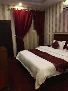 a bedroom with a large bed with red curtains at شقق أوركيد طريف للشقق المخدومة Orchida Turaif 2 2 in Ţurayf
