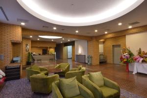 a large lobby with green chairs and a table at Daini Prince Hotel Muroran View in Muroran
