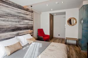 a bedroom with a bed and a red chair at Hotel Boutique La Neu in Benasque