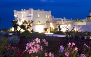 a white house at night with flowers in the foreground at Borgobianco Resort & Spa Polignano - MGallery Collection in Polignano a Mare