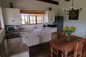 uma cozinha com armários brancos e uma mesa com flores em Out of Plett em Plettenberg Bay