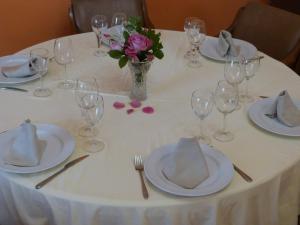una mesa con platos y vasos y un jarrón de flores en Hostal Restaurante Las Canteras en Pedrera