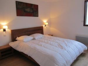 um quarto com uma grande cama branca e 2 almofadas em Les GITES DE CAMPARAN - gîte "la BERGERIE AVEC SPA" em Camparan