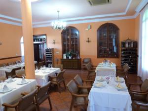 uma sala de jantar com mesas e cadeiras brancas em Hostal Restaurante Las Canteras em Pedrera