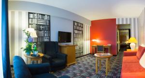- un salon avec un canapé et une télévision dans l'établissement Grünau Hotel, à Berlin
