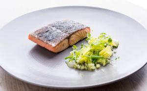 a white plate with a piece of fish and vegetables at The Swan Hotel in Southwold