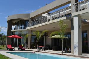 a building with a swimming pool with chairs and tables at Dante Deo Guesthouse in Bloemfontein