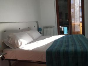 a bedroom with a bed with white sheets and a window at Le case di Pone in Cologno Monzese