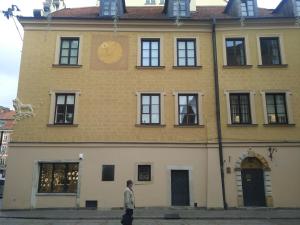 een man die voor een gebouw staat met een klok bij Świętojańska Old Town Deluxe Apartament by BookingHost in Warschau