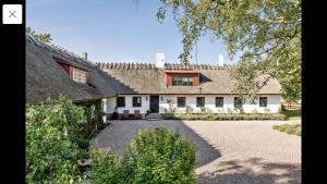 Cette grande maison blanche est dotée d'un toit de chaume. dans l'établissement Husargårdens Bed & Breakfast, à Sjöbo
