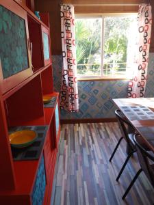 uma cozinha com armários vermelhos, uma mesa e uma janela em Huerta La Cansina em Mairena del Alcor