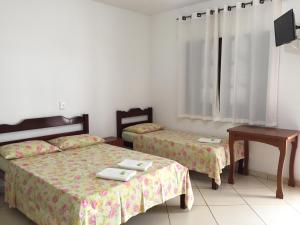 a bedroom with two beds and a table and a desk at Hotel Nossa Senhora do Carmo in Ilha Comprida +24 photos