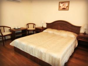 a bedroom with a bed and two tables and two chairs at Gostiniy Dvorik Guest House in Yaroslavl