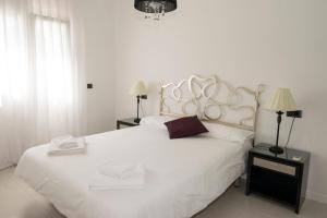 1 dormitorio con 1 cama blanca con 2 mesitas de noche y 2 lámparas en Parques Casablanca, en Benissa