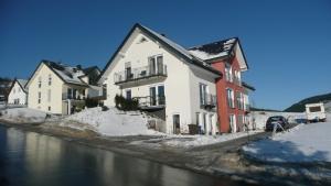 eine Gruppe von Gebäuden neben einem Fluss mit Schnee in der Unterkunft Kleines Ritz in Willingen