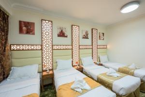 Habitación con 4 camas y 2 ventanas. en Rawdhat Al Mukhtara Hotel, en Medina