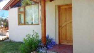 a door to a house with purple flowers next to it at Cabaña Rufus in Lago Puelo