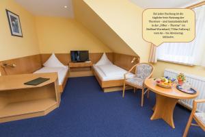 Habitación pequeña con 2 camas y mesa. en Hotel Restaurant Waldmühle, en Wolkenstein