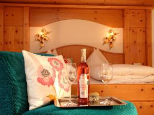 a bed with a tray with wine bottles and glasses at Pension Katharinenhof uzavřen in Kaprun