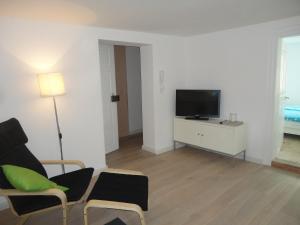 uma sala de estar com uma televisão de ecrã plano e cadeiras em Schönerferienwohnen in Bamberg em Bamberg
