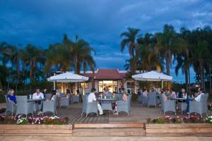 a group of people sitting at tables with umbrellas at Green Village Hotel e Restaurante in Santa Bárbara do Rio Pardo +35 photos