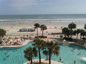 een zwembad naast een strand met palmbomen bij Ocean Walk Resort 603ii in Daytona Beach