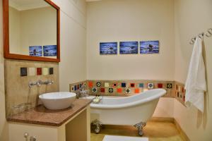 a bathroom with a tub, sink, mirror and bathtub at Bayete Guest Lodge in Victoria Falls