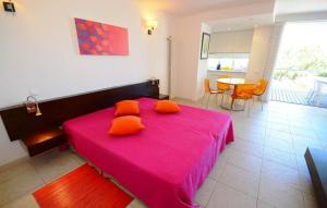 a bedroom with a pink bed with orange pillows at Modern Golden Apartment in Cabanas de Tavira