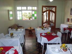 ein Esszimmer mit weißen Tischen, Stühlen und Fenstern in der Unterkunft Majestic Hotel in Juiz de Fora