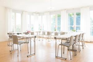 a dining room with white tables and chairs and windows at 1909 Sigtuna Stads Hotell in Sigtuna