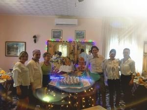 een groep mensen die rond een tafel met een taart staan bij Hotel Edera in Lido di Jesolo