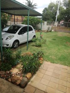 un coche blanco aparcado en un patio con una tienda de campaña en MulMas Guest House, en Pretoria