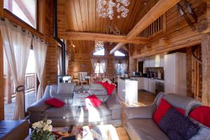 a living room with couches and a kitchen in a cabin at Odalys Chalet Leslie Alpen in Les Deux Alpes