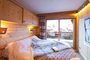 een slaapkamer met een bed en een groot raam bij Odalys Chalet Husky in Les Deux Alpes