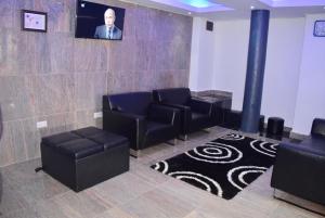 een wachtkamer met zwarte stoelen en een tv bij Latitude 1 Suites in Kampala