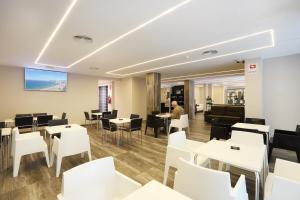 un restaurante con mesas blancas y sillas blancas en Hotel Alameda, en Benidorm