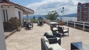 eine Terrasse mit Stühlen und Tischen und Blick auf das Wasser in der Unterkunft Hotel El Faro in Villa Carlos Paz