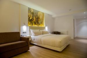 Un dormitorio con una cama blanca y un sofá. en Taste Hotel Heidenheim, en Heidenheim an der Brenz