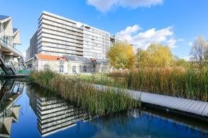 a building next to a river with tall grass at ibis Paris 17 Clichy-Batignolles (ex Berthier) in Paris