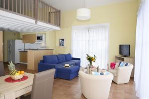 a living room with a blue couch and a table at Résidence Odalys Les Greens du Bassin in Gujan-Mestras