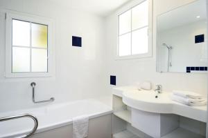 a white bathroom with two sinks and a mirror at Résidence Odalys Les Greens du Bassin in Gujan-Mestras
