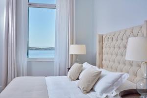 a bedroom with a white bed with a window at Poseidonion Grand Hotel in Spetses